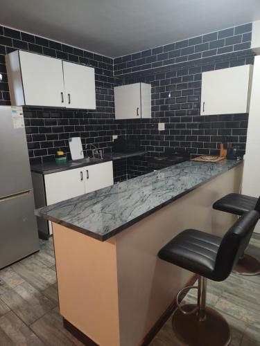 cocina con encimera de granito y azulejos negros en Ocean view @ 10 south, en Durban
