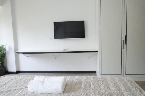 a white bedroom with a tv on a white wall at VIYA Residence in Ban Phala