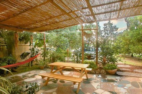 a wooden picnic table under a wooden pergola at ביקתפוז וקלמנטינה- מתחם בקתות וסוויטות עם ג'קוזי פרטי ובריכה משותפת in Liman