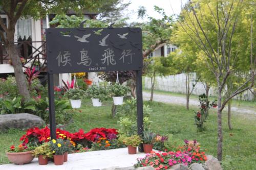 a sign in a garden with flowers and plants at Hou Niao Fei Xing B&B in Taiping