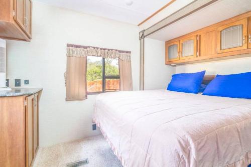 sypialnia z łóżkiem z niebieskimi poduszkami i oknem w obiekcie Moab RV Resort Outdoor Glamping Destination RV OK40 w mieście Moab