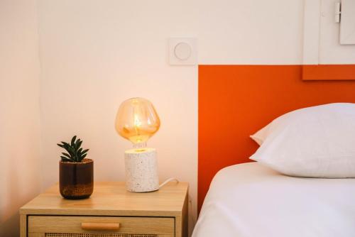 una lámpara en una mesita de noche junto a una cama en L'Air Marin - Calm & cosy house by the sea en Ouistreham