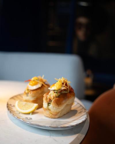 two sandwiches on a plate with a slice of lemon at Andaz Amsterdam, Prinsengracht, By Hyatt in Amsterdam