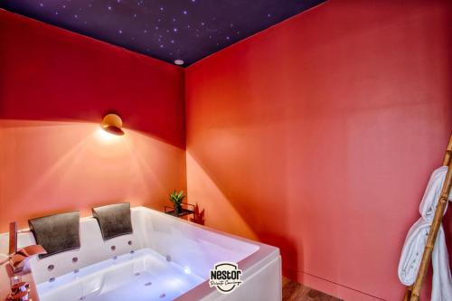 - une baignoire dans une chambre aux murs rouges dans l'établissement Casa Amour — Balneo, cosy & relaxation, à Caen