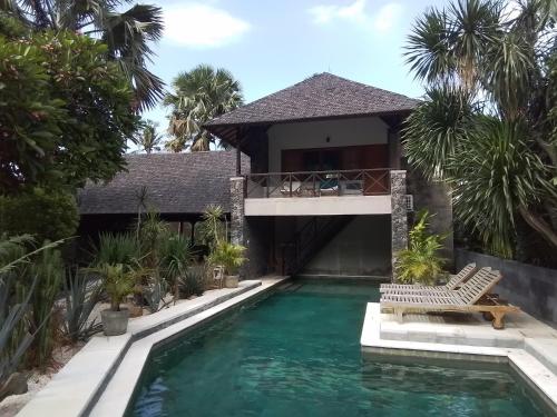 a villa with a swimming pool and a house at Villa del Mar Amed Bali in Amed