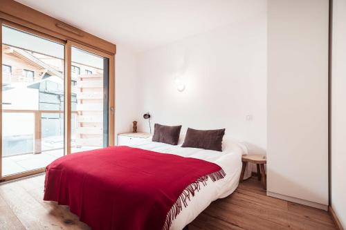 une chambre avec un grand lit avec une couverture rouge dans l'établissement Flat Crystal at the summit of Combloux, à Combloux