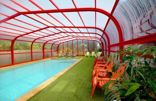 an indoor pool with chairs and a swimming pool at ביקתפוז וקלמנטינה- מתחם בקתות וסוויטות עם ג'קוזי פרטי ובריכה משותפת in Liman