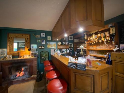 um bar com lareira e bancos vermelhos em Lodge Hôtel de Sommedieue Verdun em Sommedieue