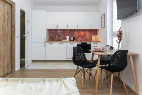 a kitchen with white cabinets and a table and chairs at D127 Apartament Romeo in Lublin