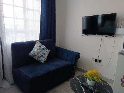 einen blauen Stuhl im Wohnzimmer mit einem TV in der Unterkunft Ruby in Nairobi
