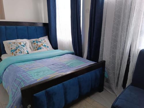 ein Schlafzimmer mit einem blauen Bett und einem Fenster in der Unterkunft Ruby in Nairobi