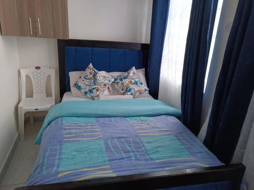Bett mit blauem Kopfteil in einem Schlafzimmer in der Unterkunft Ruby in Nairobi