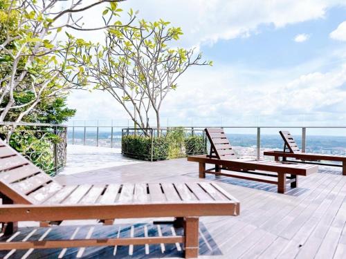dois bancos de madeira sentados num deque com vista para o oceano em Silverscape Seaview Residence Melaka em Malaca