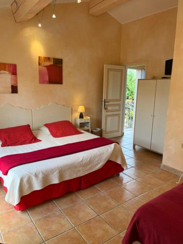 a bedroom with a large bed with red pillows at Le Mazet des Mûres in Grimaud