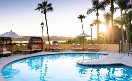 a pool at a resort with chairs and palm trees at Datu - Discover world with us in Newport Beach