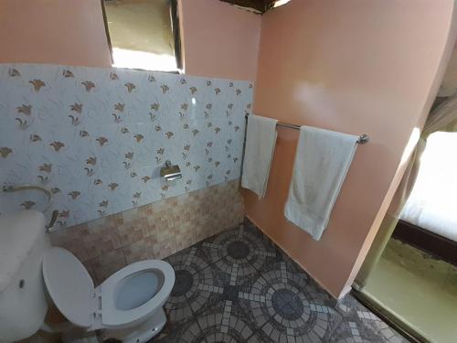 a bathroom with a toilet and a sink and towels at Mara Olodare in Ololaimutiek