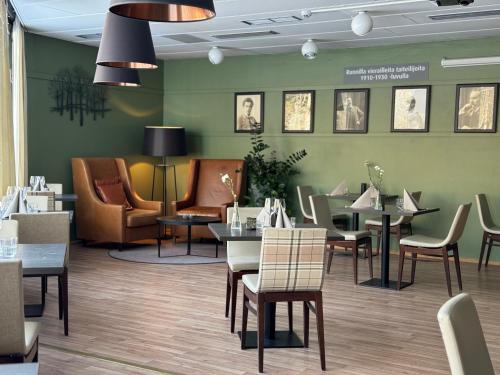 restauracja ze stołami i krzesłami oraz zieloną ścianą w obiekcie Spa Hotel Runni Iisalmi w mieście Iisalmi