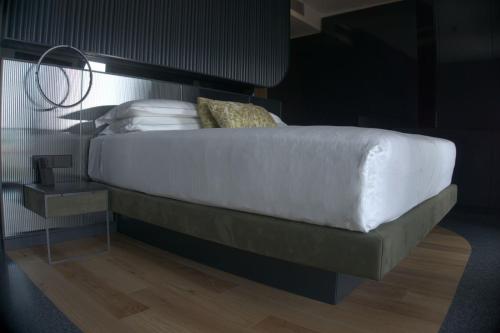 a bed with white sheets and pillows on it at Hotel Ristorante Al Caminetto WorldHotels Crafted Adults Only in Torri del Benaco