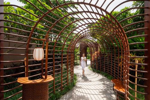 a woman walks through an archway with plants at New World Hoiana Beach Resort in Hoi An