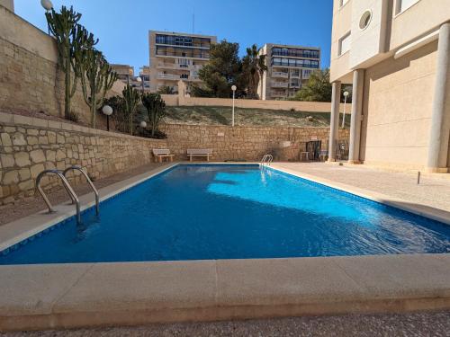 een groot blauw zwembad naast een gebouw bij Apartamento sol y dunas in Arenales del Sol