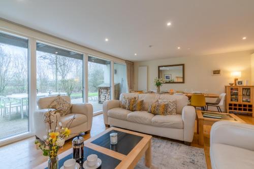 a living room with two couches and a table at Songthrush in Somerford Keynes