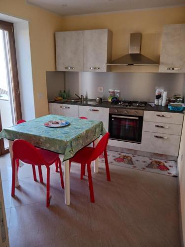 a kitchen with a table and two red chairs at Cappuccini Guest House in San Giovanni in Fiore