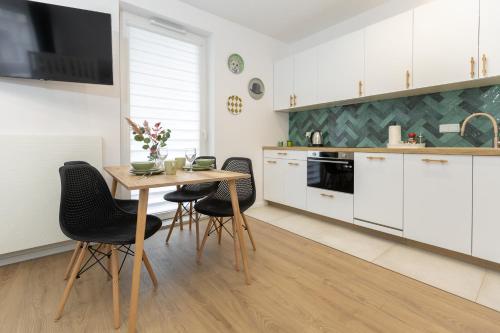 una cocina con armarios blancos y una mesa y sillas de madera. en D127 Apartament Rodzinny Sierra, en Lublin