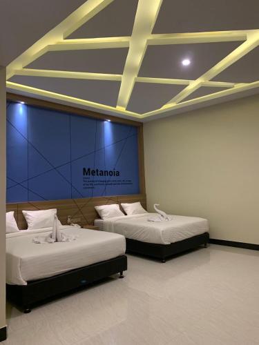 two beds in a room with a sign on the wall at Bless Hotels in Sintang