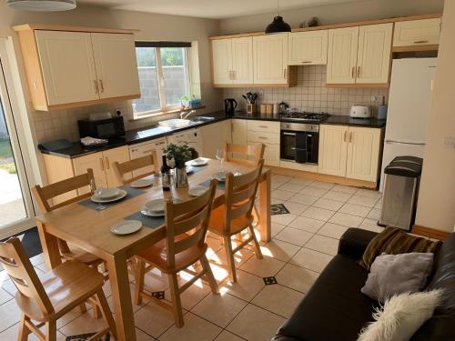 a kitchen with a wooden table and chairs and a table and a kitchen with at Tramore Holidays in Tramore