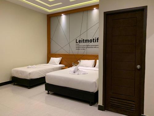 two beds in a room with a sign on the wall at Bless Hotels in Sintang