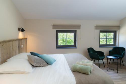 a bedroom with a large white bed with two chairs at B & B De Romeinse Katzei in Borgloon