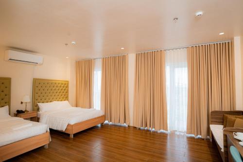 JVJ HOTELS CORPORATION في باتانجاس سيتي: غرفة نوم بسريرين ونافذة كبيرة