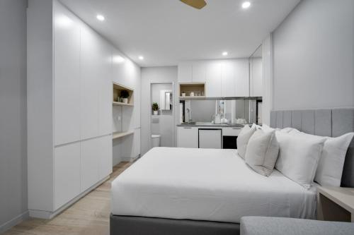 a white bedroom with a bed and a couch at Belmoral Corporate Suites in Townsville