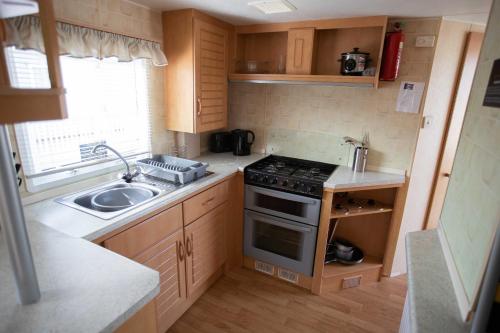a small kitchen with a stove and a sink at Skegness Caravans in Skegness