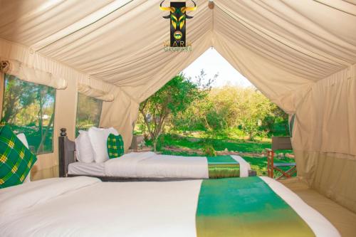 a bedroom with two beds in a tent at Mara Olodare in Ololaimutiek