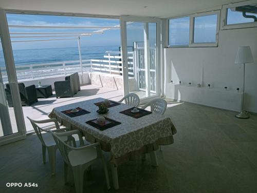ein Esszimmer mit einem Tisch, Stühlen und Meerblick in der Unterkunft PALOMERA LUXURY APARTMENT SUL MARe in Gaeta