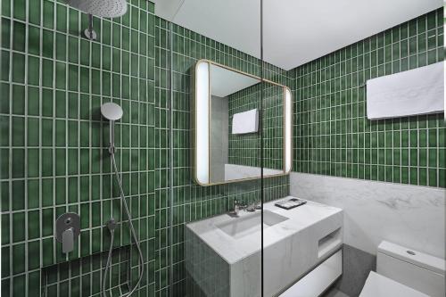 a green tiled bathroom with a sink and a mirror at ARTOTEL Casa Kuningan in Jakarta