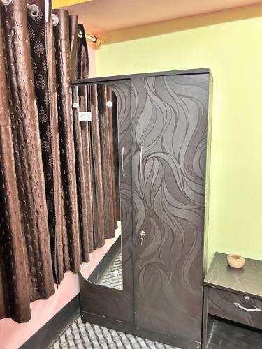 Habitación con una puerta con cortinas marrones en Sweet Home Lodge, en Guwahati