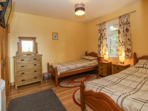 1 Schlafzimmer mit 2 Betten, einer Kommode und einem Fenster in der Unterkunft Alba Ben View in Spean Bridge