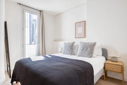 a white bedroom with a bed and a window at Renovated La Dreta de lEixample 1br w balcony BCN-89 in Barcelona