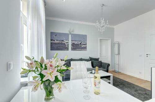 een witte woonkamer met een vaas met bloemen op een tafel bij Platinum Residence - Chmielewskiego in Sopot