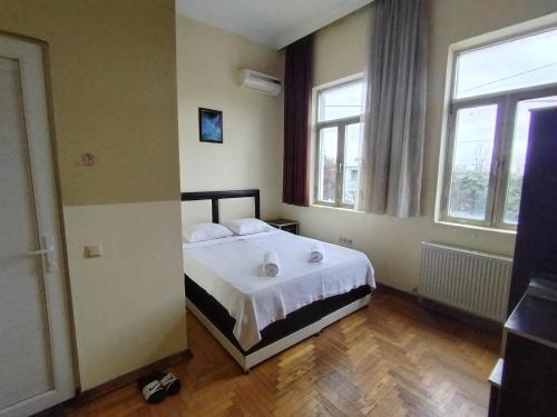 1 Schlafzimmer mit einem Bett mit weißer Bettwäsche und 2 Fenstern in der Unterkunft BK GOLD HOTEL in Batumi