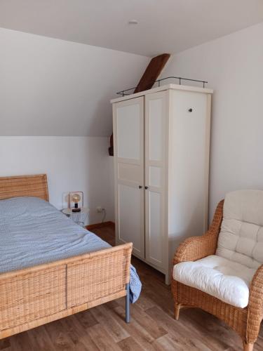 een slaapkamer met een bed, een kast en een stoel bij La petite ferme in Saint-Pierre-des-Nids