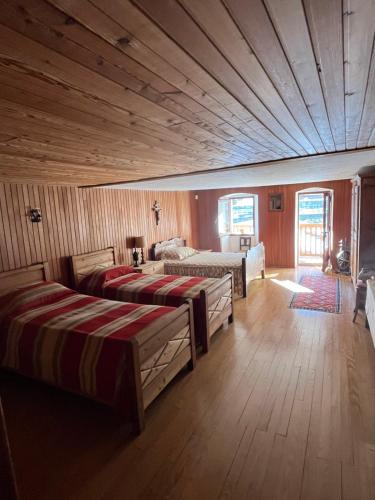 a bedroom with two beds and a wooden ceiling at L'Atelier du Temps - Casa Ronc in Etroubles