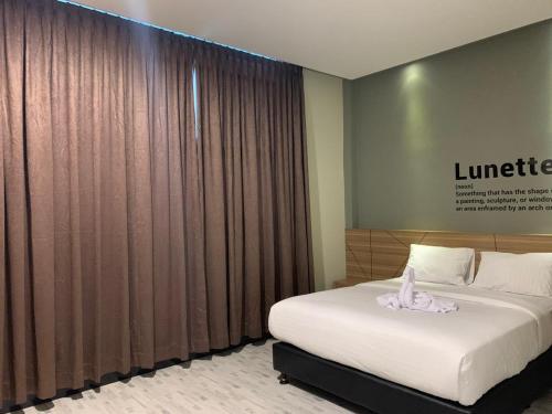 Habitación de hotel con cama y cartel en la pared en Bless Hotels en Sintang
