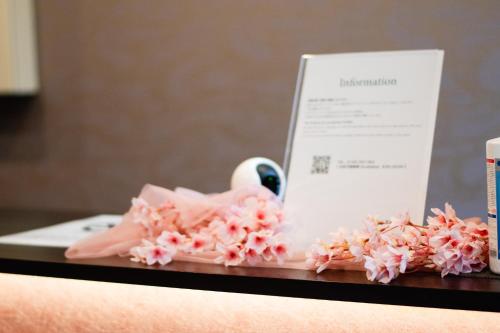 a table topped with pink flowers and a piece of paper at Hotel Neiraku in Nara