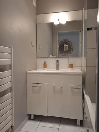 une salle de bain blanche avec un lavabo et un miroir dans l'établissement Appartement tout équipé proche General Electric, à Belfort