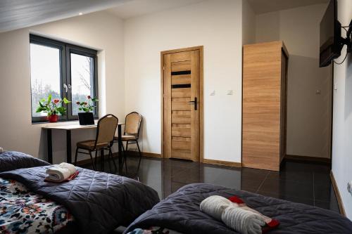 Cette chambre comprend deux lits, une table et un bureau. dans l'établissement KR Pokoje, à Tokarnia