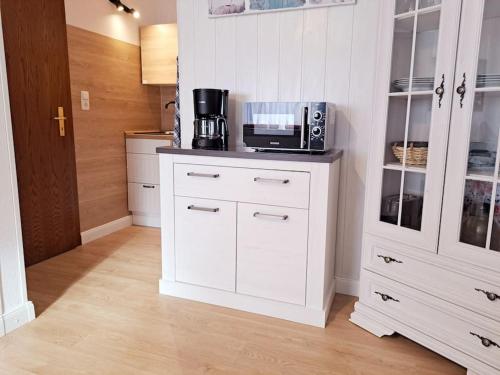 a kitchen with white cabinets and a microwave at Ruhiges 1-Zimmer-Appartement, Büsum (4km), Nordsee in Oesterdeichstrich