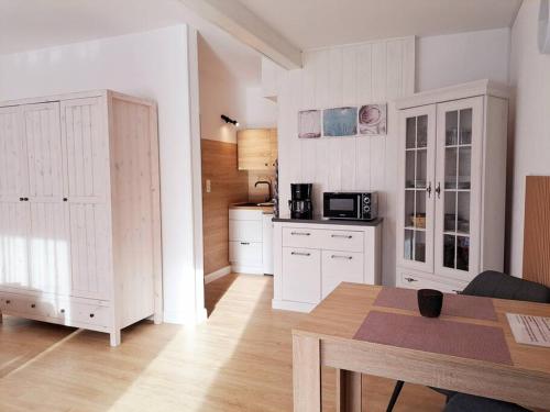 a kitchen with white cabinets and a table in a room at Ruhiges 1-Zimmer-Appartement, Büsum (4km), Nordsee in Oesterdeichstrich